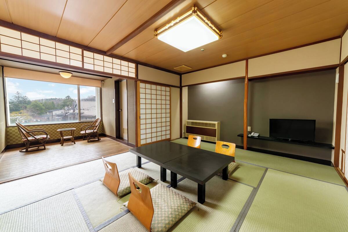 Une pièce de style japonais traditionnel, avec un sol recouvert de tatamis, une table basse et des portes coulissantes.