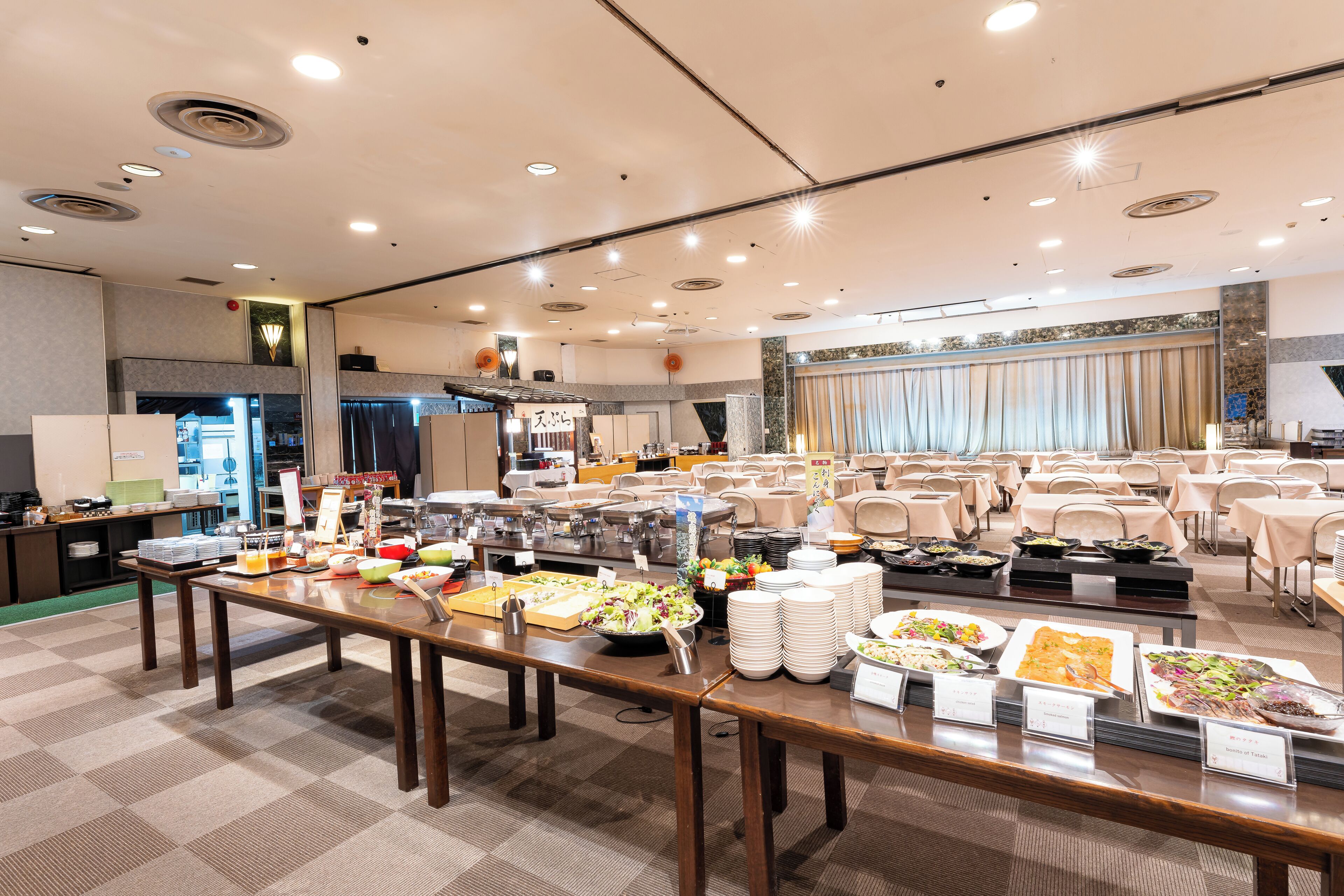 A buffet setup with various food stations and a seating area with tables and chairs.