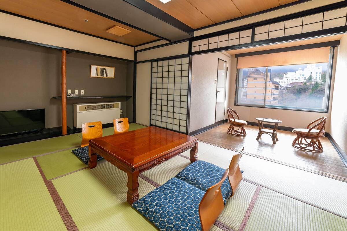 Une pièce de style japonais traditionnel, avec un sol recouvert de tatamis, une petite table en bois et une porte coulissante.