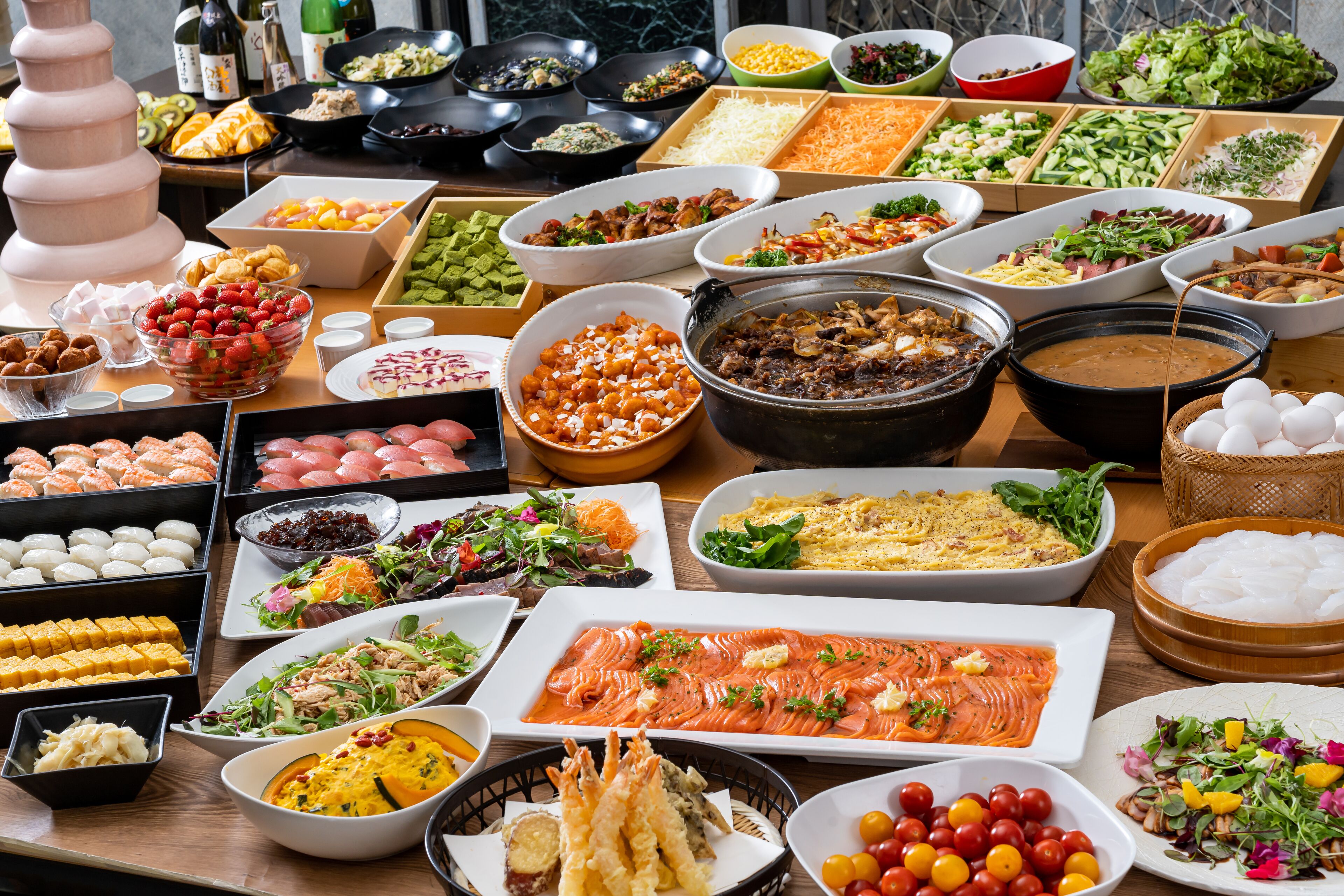 Un bufé con diversos alimentos, como ensaladas, carnes y mariscos.