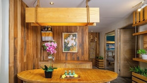 Een houten bar met een ronde tafel, planten in potten en een hanglamp.