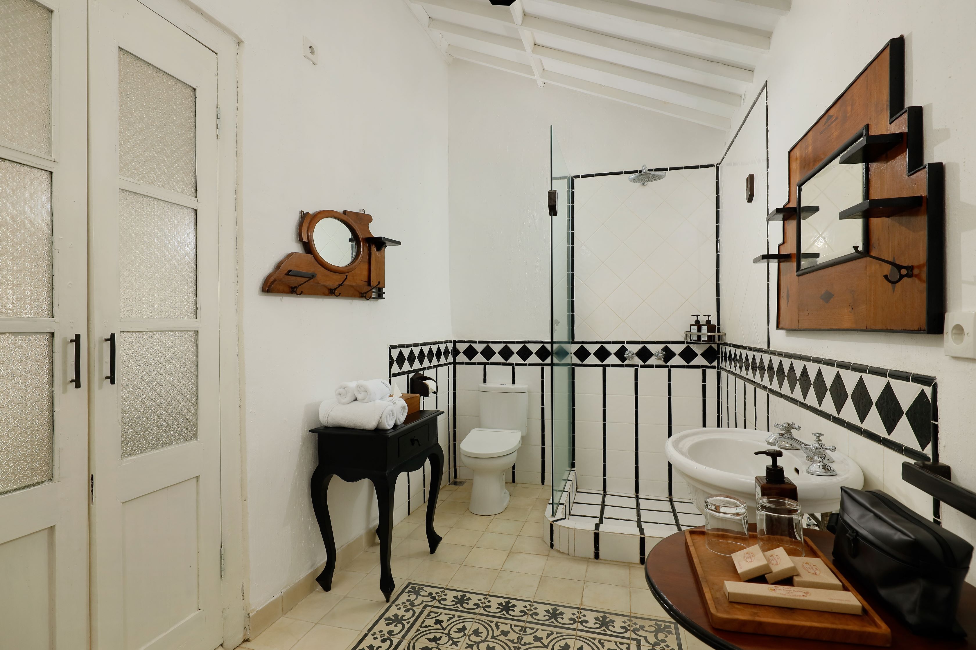 Un baño con inodoro blanco, lavabo, espejo y zona de ducha.
