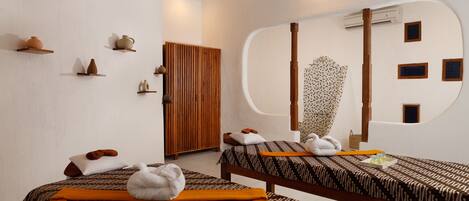 A spa room with two beds, a wooden cabinet, and a large mirror.
