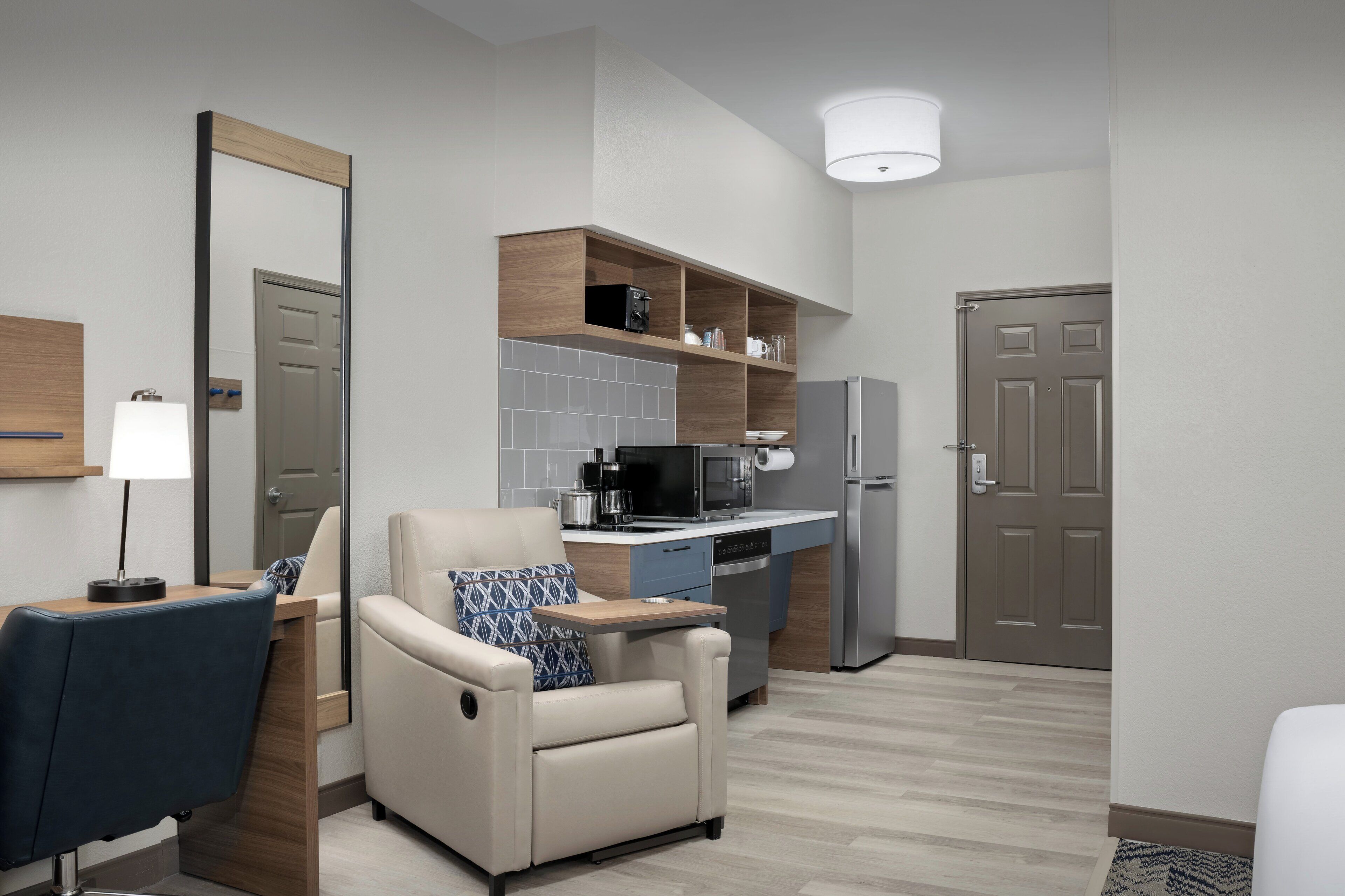 A compact living space with a kitchenette, a sofa, a chair, and a dining table.