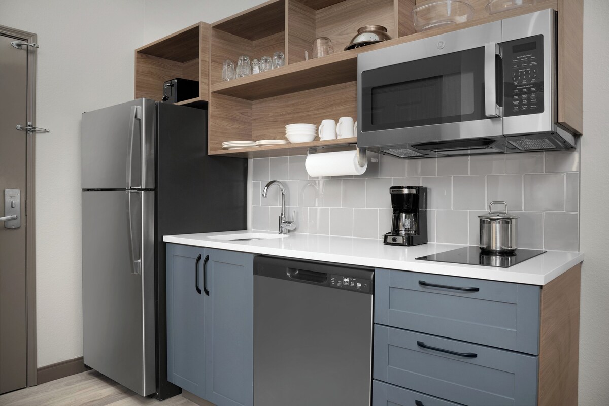 A modern kitchen with a stainless steel refrigerator, a built-in microwave, a dishwasher, and a coffee maker.