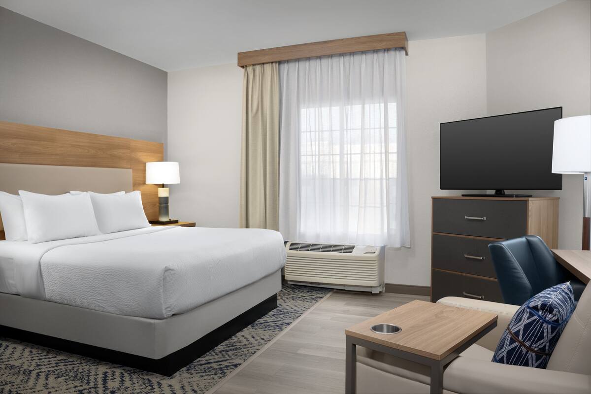 A hotel room with a bed, a desk, a television, and a chair.