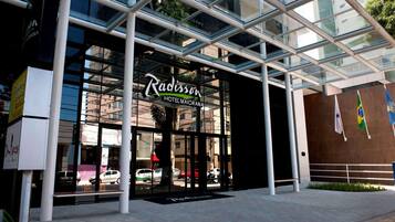 Entrada do Hotel Radisson Majorana, com portas de vidro e design arquitetônico moderno.