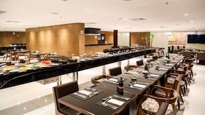 Un restaurante moderno con una barra alargada, varias mesas para comer y una variedad de platos exhibidos.