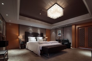 A spacious bedroom with a large bed, a bench, a desk, and a chair.