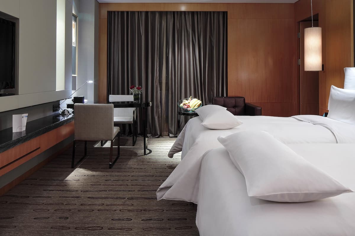 A hotel room with a bed, a desk, a chair, a mirror, and a curtain.