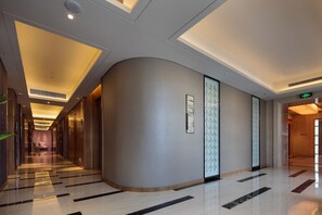 Un pasillo moderno de hotel con pared curva, iluminación empotrada y suelo pulido.