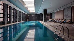 A swimming pool with a clear view of the ceiling, a sunroof, and a row of lounge chairs along the side. - Pullman Anshan Time Square (Anshan)