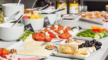A buffet with various food items including fruits, cheeses, and meats.