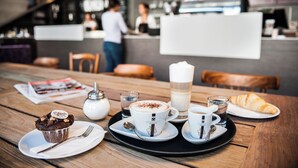A dining table with a muffin, a tall glass of milk, and a croissant.