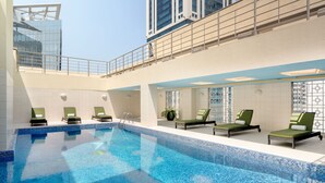 A large indoor swimming pool with lounge chairs and a high ceiling with a glass section. - Marriott Executive Apartments City Center Doha (Doha)