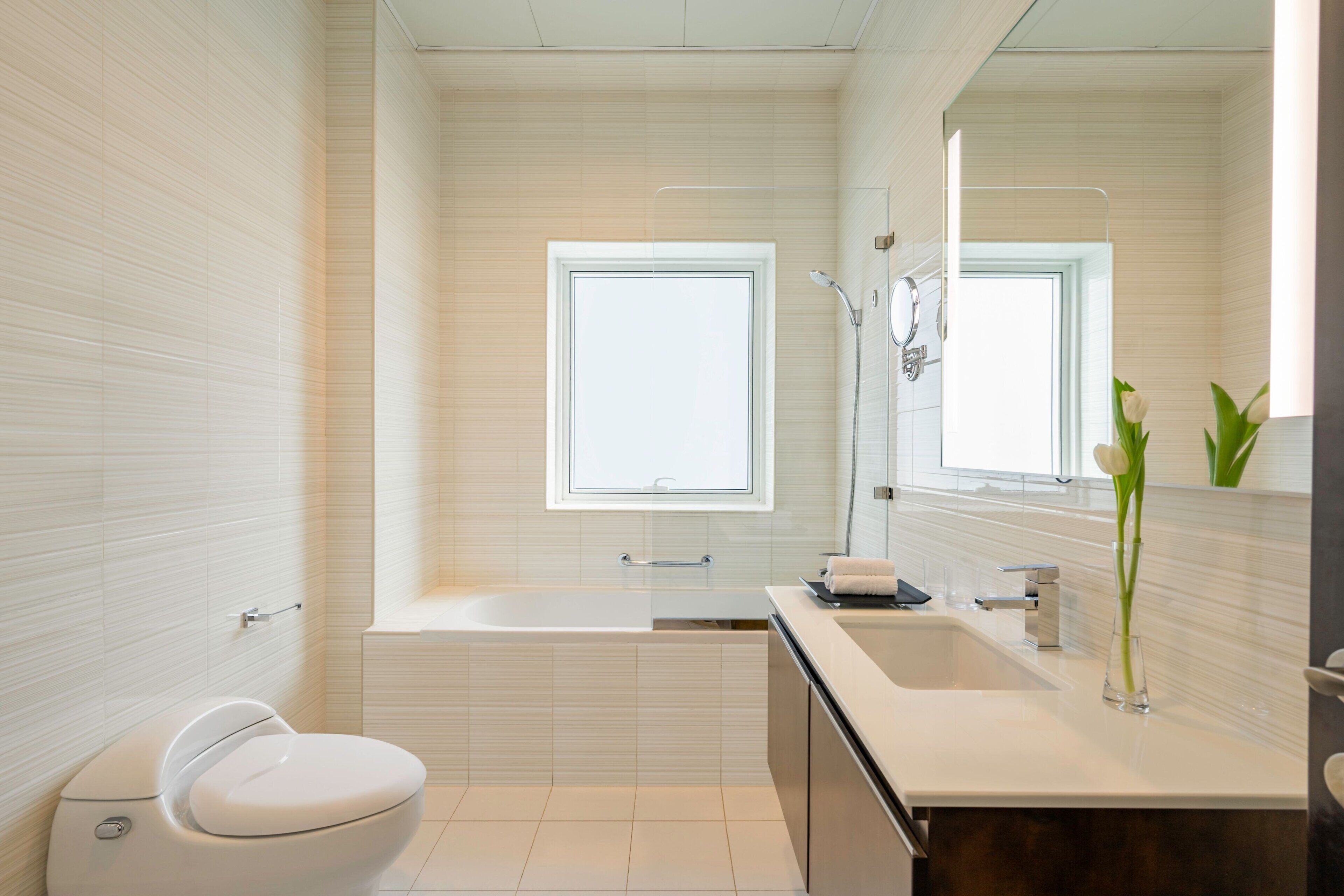 A modern bathroom with a toilet, bathtub, and sink.
