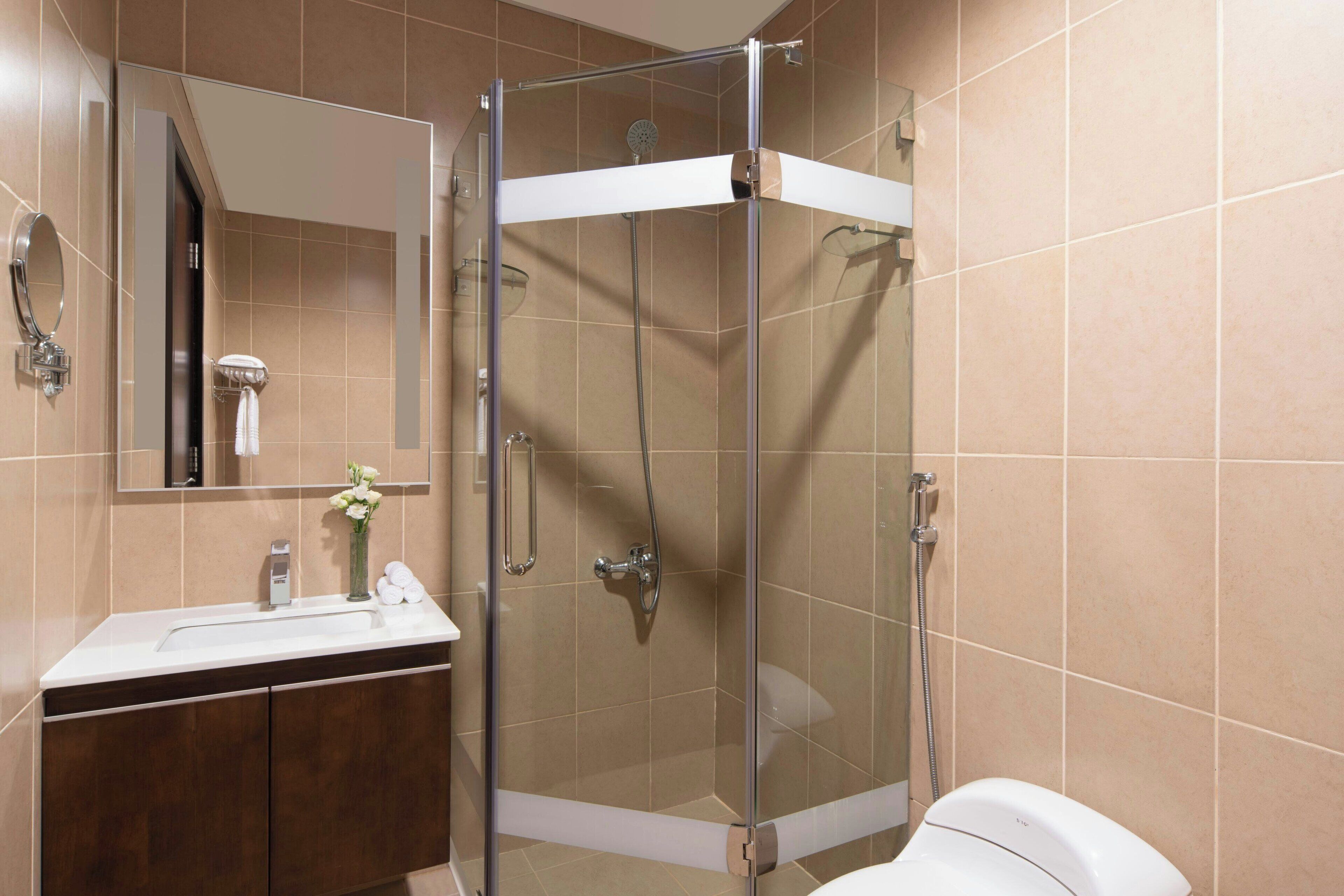 A modern bathroom with a glass-enclosed shower, a vanity with a mirror, and a toilet.