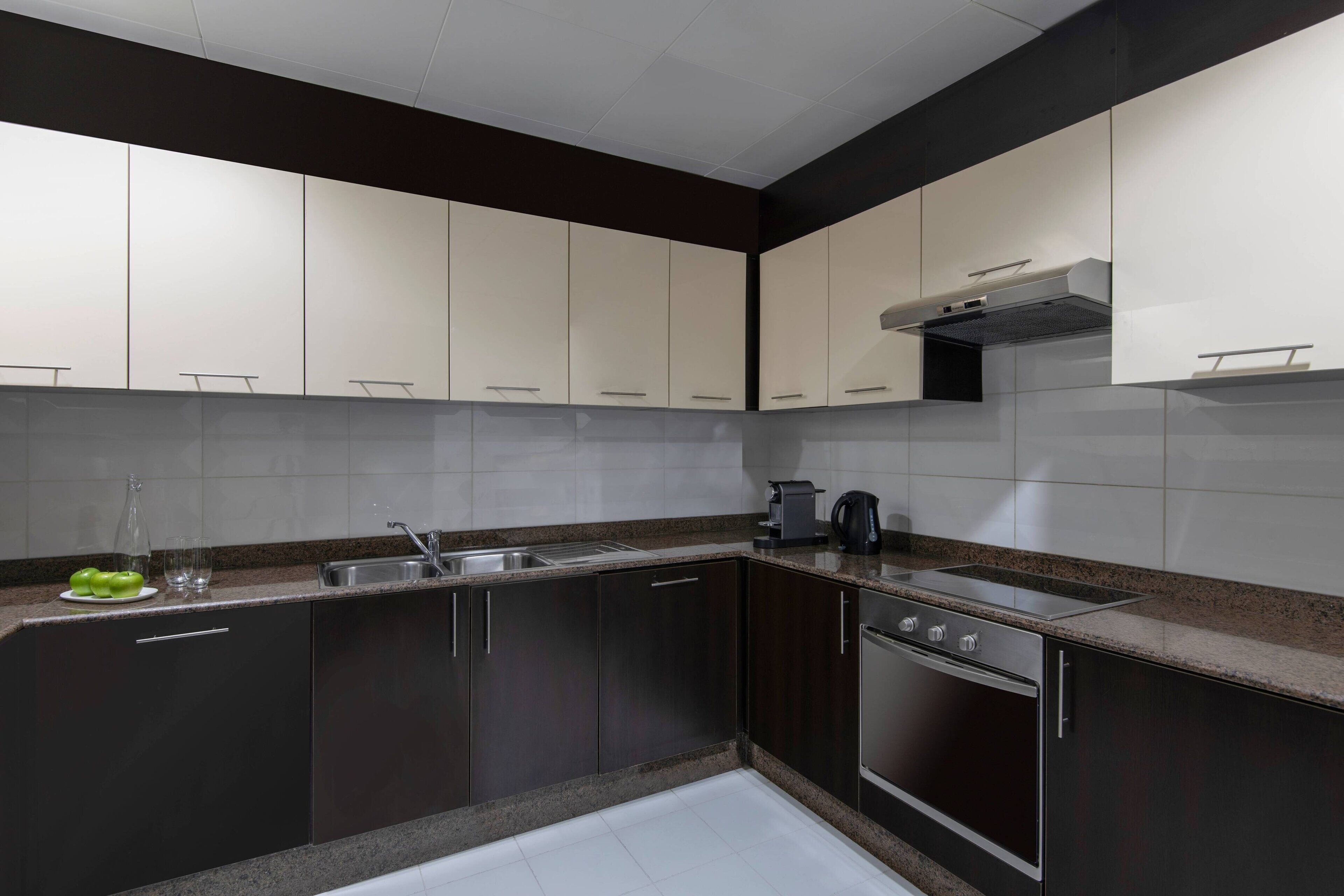 A modern kitchen with dark cabinets, a stainless steel sink, and a built-in oven.