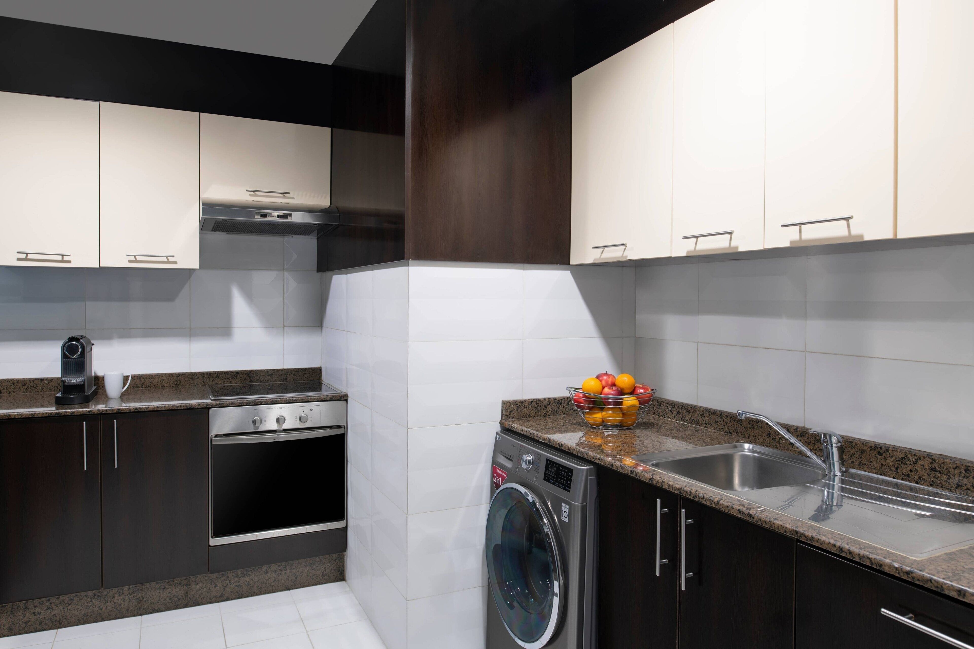 A modern kitchen with dark cabinetry, stainless steel appliances, and a granite countertop.