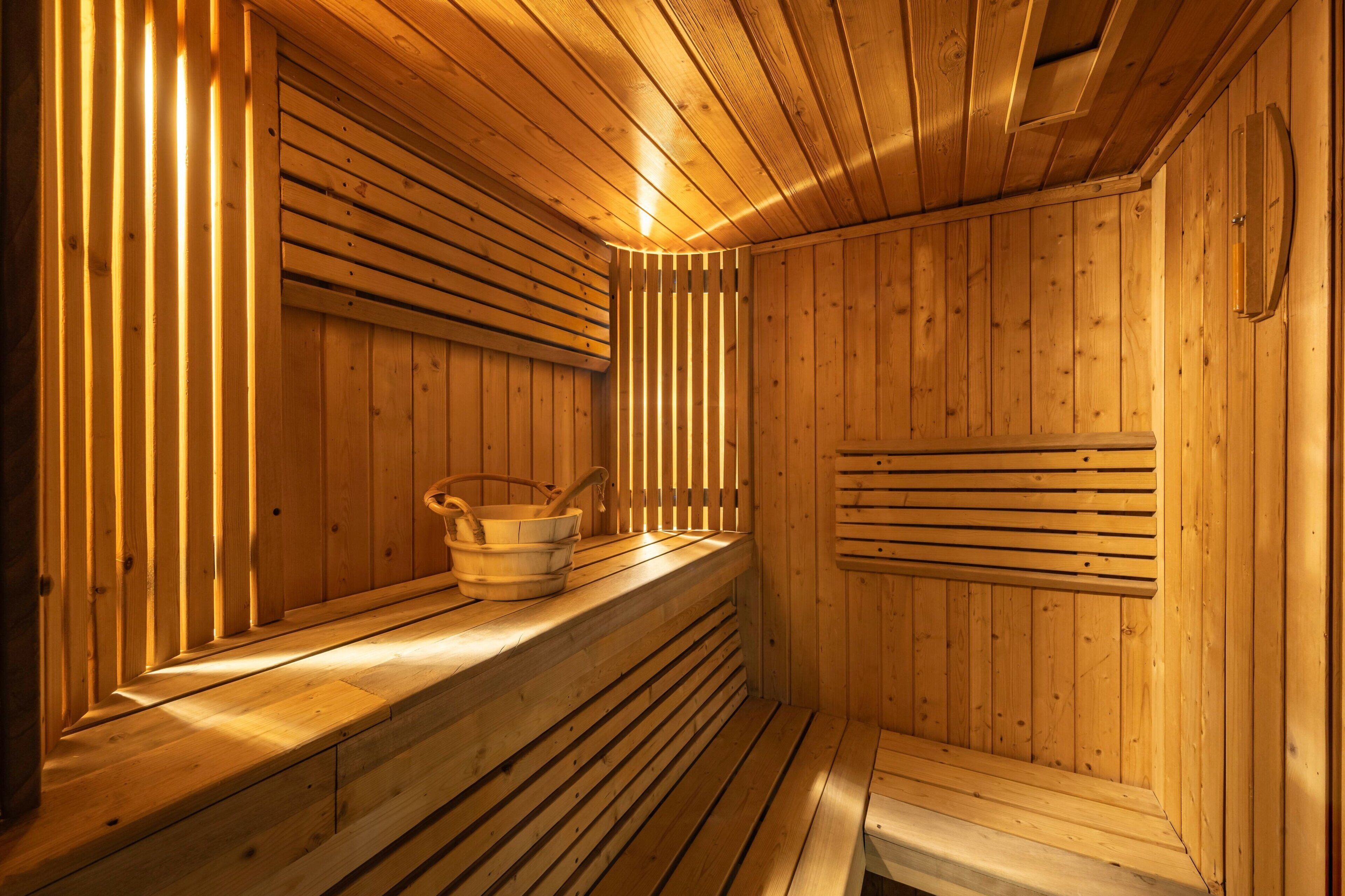 A wooden sauna with benches and a bucket.