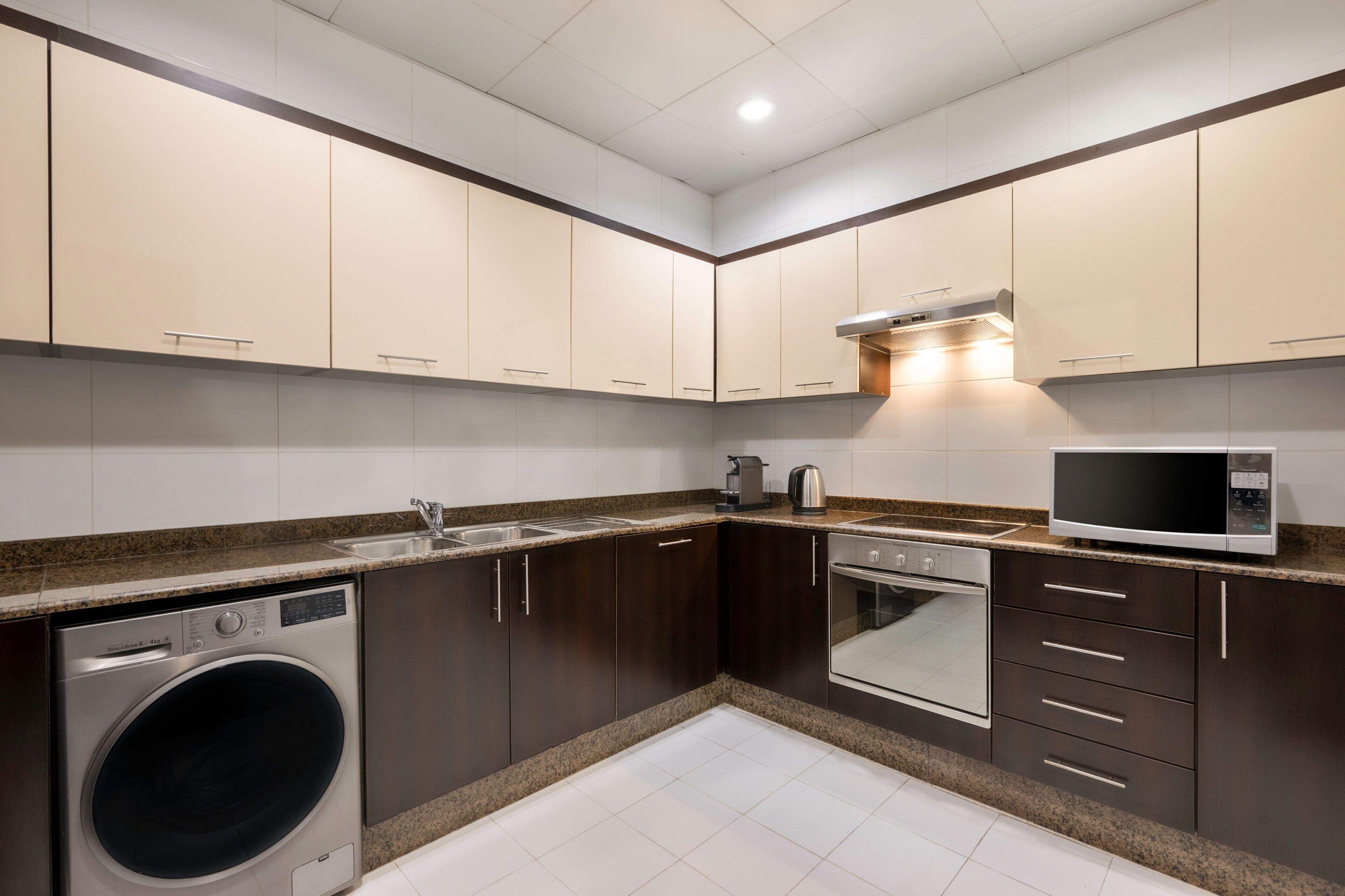 A modern kitchen with dark cabinets, a built-in washing machine, a microwave, and a stove.