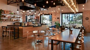 A modern cafe with exposed brick walls, wooden furniture, and pendant lighting. - Marriott Executive Apartments City Center Doha (Doha)