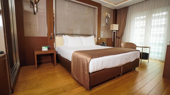 Una habitación de hotel con una cama grande, una mesita de noche, una silla y una lámpara.