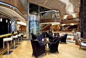 A modern hotel lobby with a bar area, seating, and a glass elevator. - Holiday Inn Ankara - Kavaklidere by IHG (Ankara)