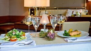 A dining table set with plates of food, glasses of wine, and a decorative centerpiece.
