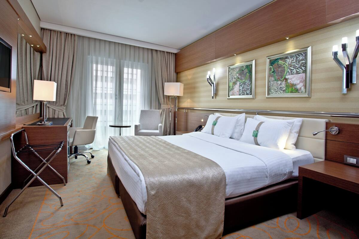 A hotel room with a bed, desk, chair, and a TV.