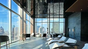 A modern lounge with large windows, a city view, and a mix of seating options. - Regent Shanghai Pudong (Shanghai)