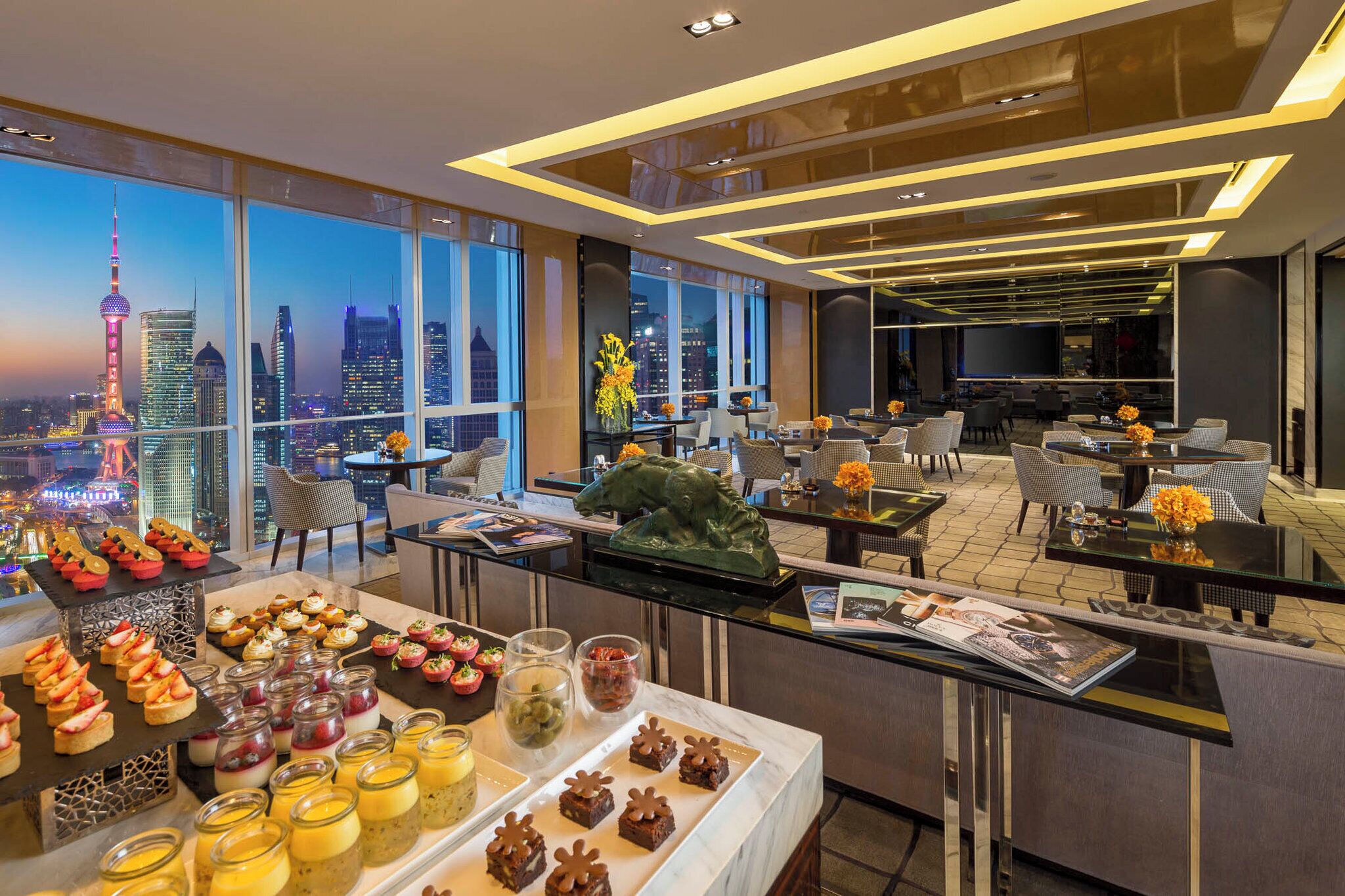 Un moderno vestíbulo de hotel con una vista panorámica de la ciudad, una recepción y un área de comedor con una variedad de alimentos y bebidas.