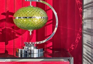 A green glass globe with a chrome stand against a red background.