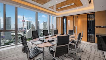 Una sala de conferencias moderna con vista panorámica de la ciudad, amplias ventanas y un techo alto con iluminación empotrada.