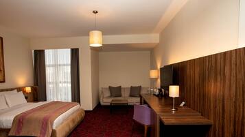 Une chambre d’hôtel avec un lit, un canapé, un bureau et une télévision.