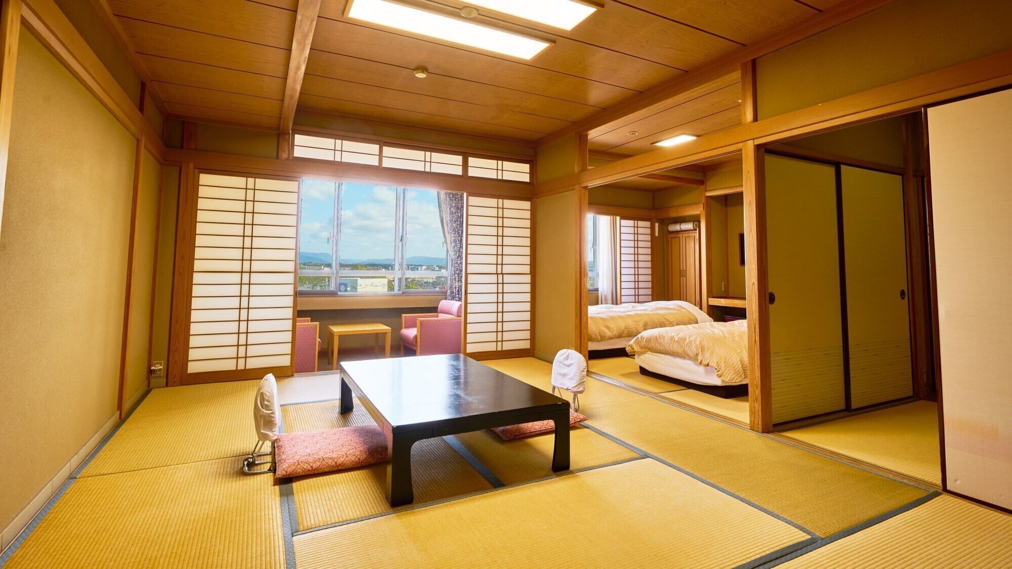 A traditional Japanese room with tatami flooring, a low table, a sofa, and a sliding door.