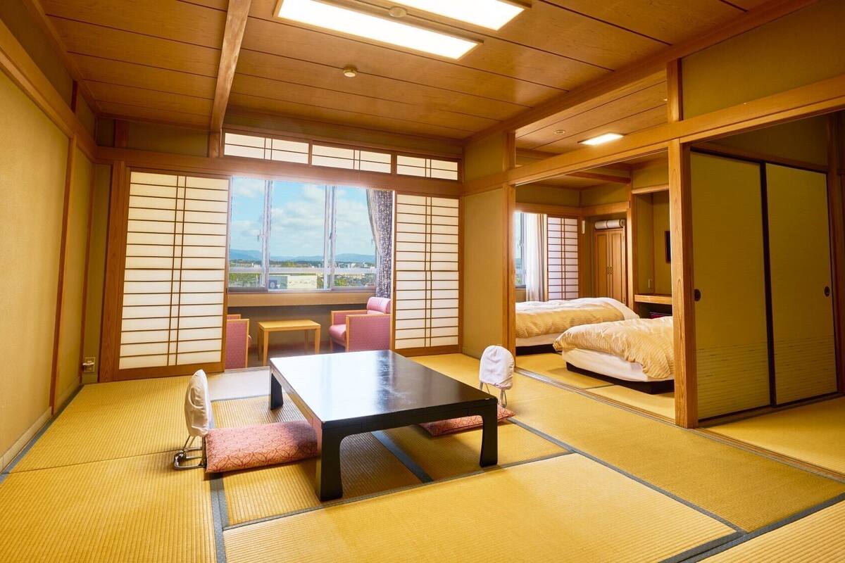 A traditional Japanese room with tatami flooring, a low table, a sofa, and a sliding door.