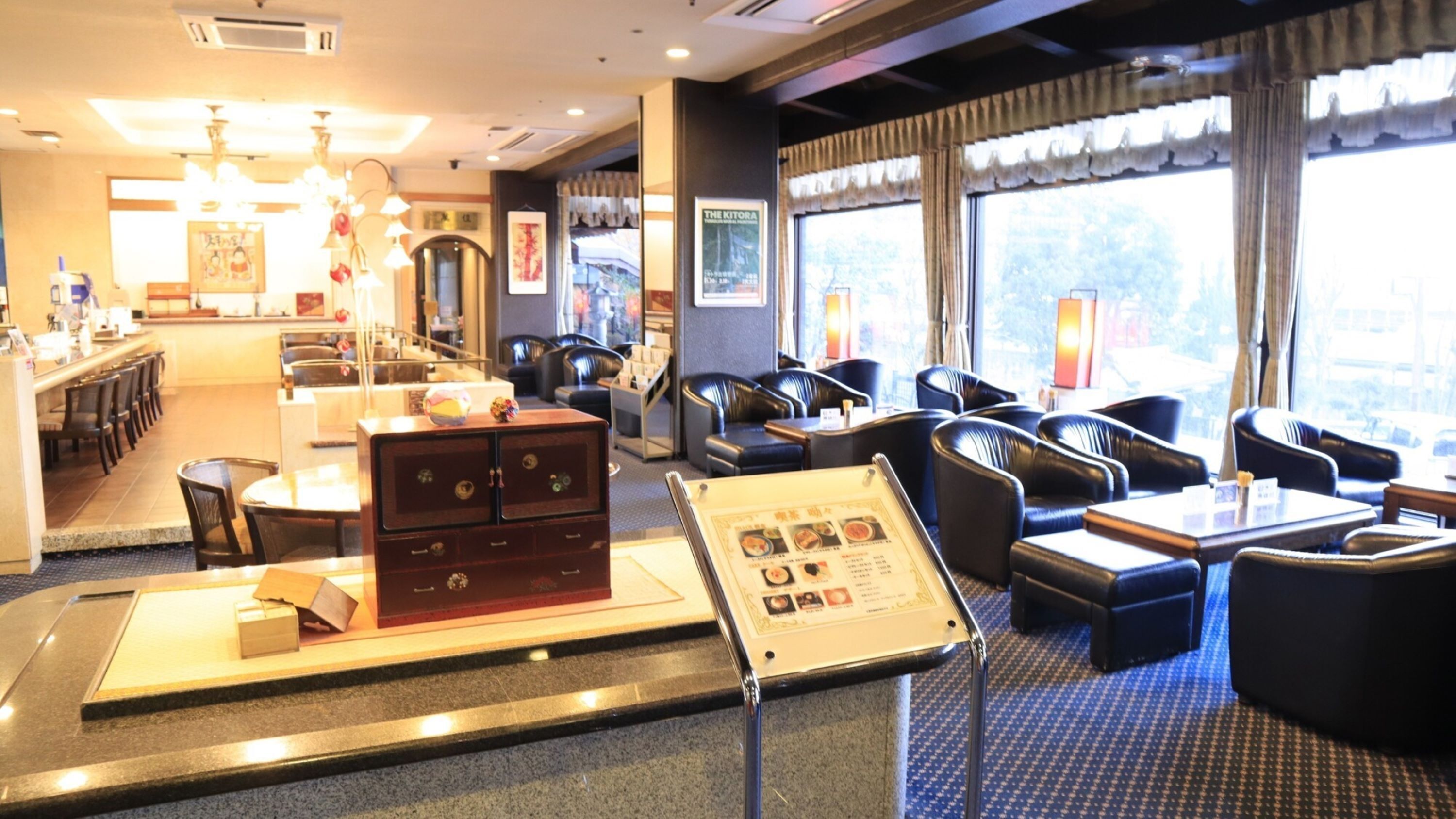 Un hall d’hôtel comprenant un comptoir d’accueil, un espace salon et un présentoir à menus.