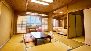 A traditional Japanese room with tatami flooring, a low table, two beds, and sliding doors. - Nara Park Hotel (Nara)