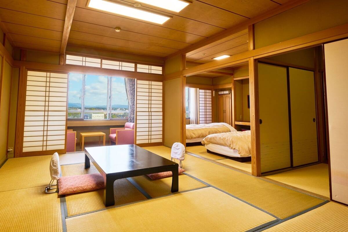 A traditional Japanese room with tatami flooring, a low table, two beds, and sliding doors.
