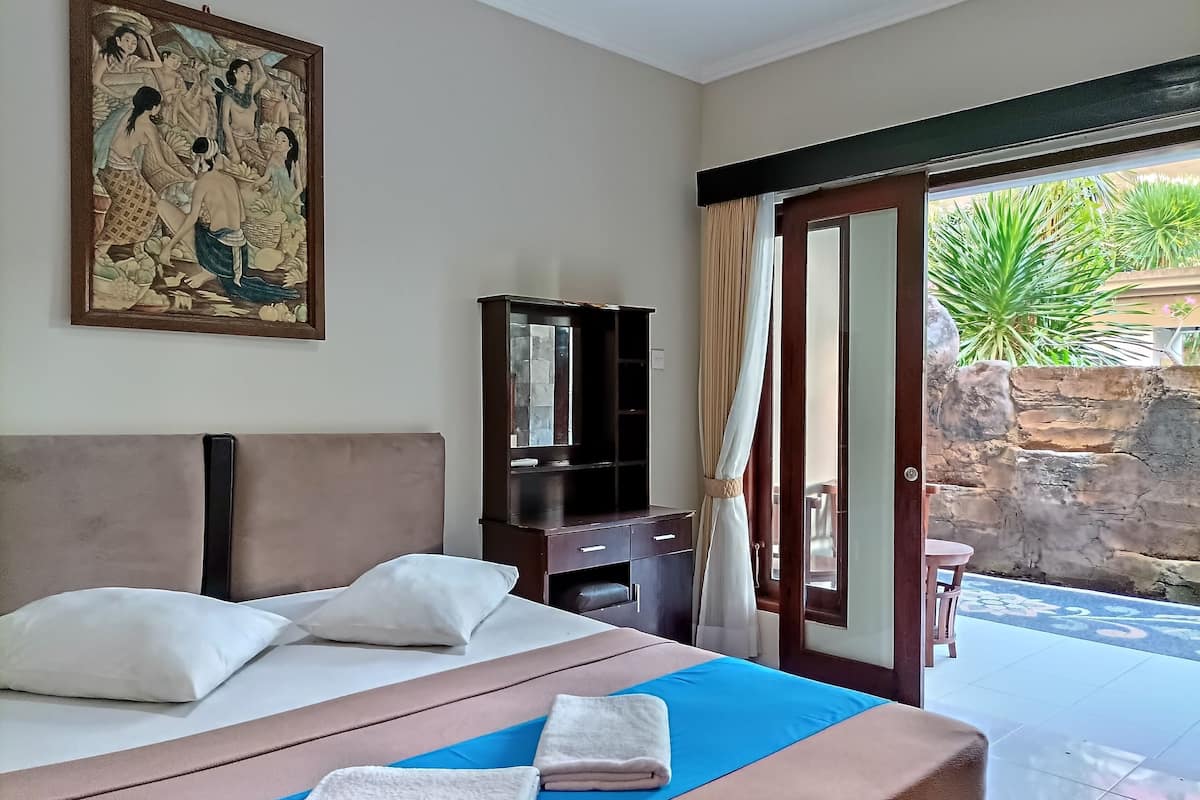 A hotel room with a bed, a nightstand, a mirror, and a painting on the wall.