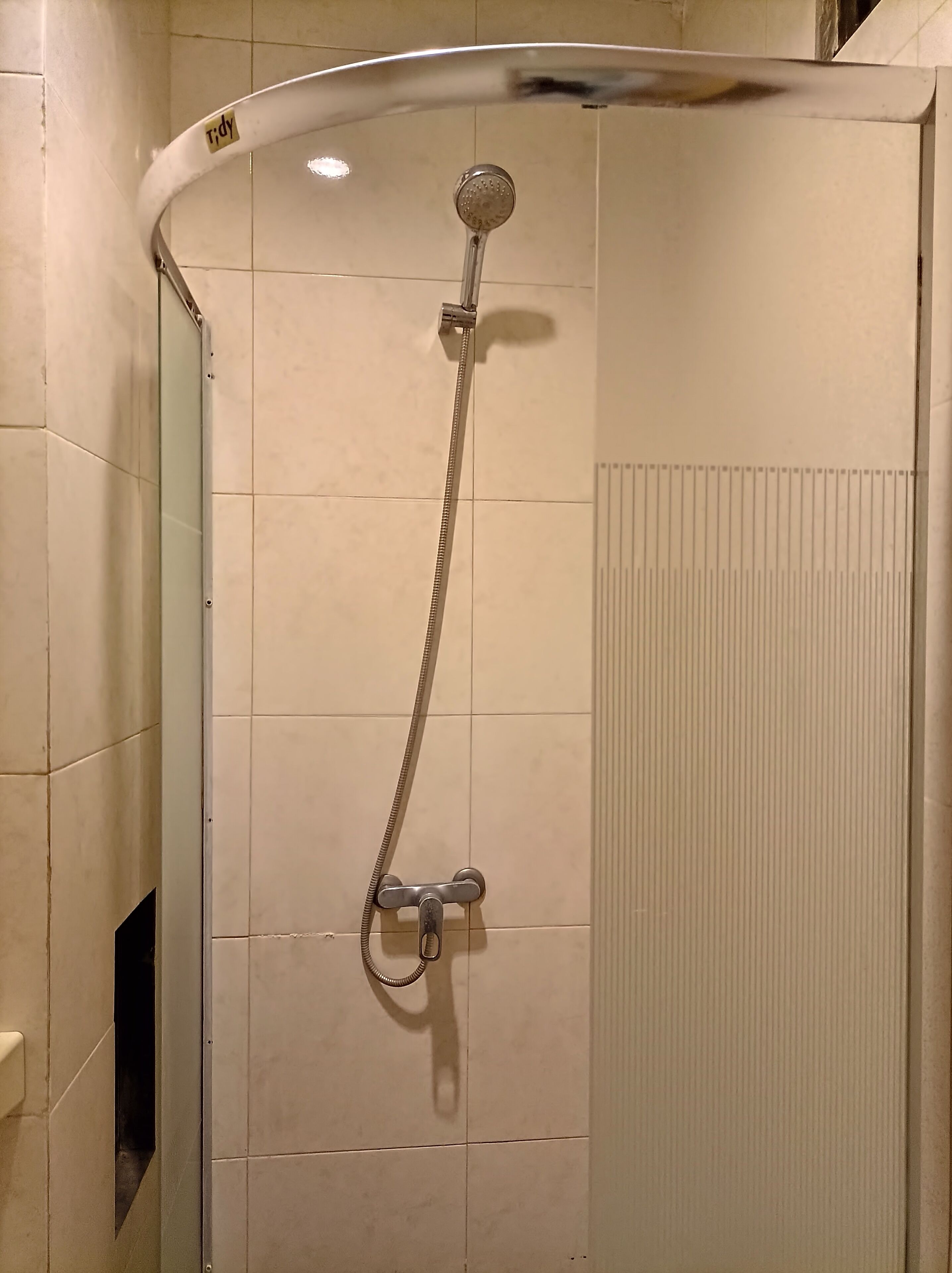 Une douche dotée d’un pommeau de douche incurvé et d’un flexible de douche.