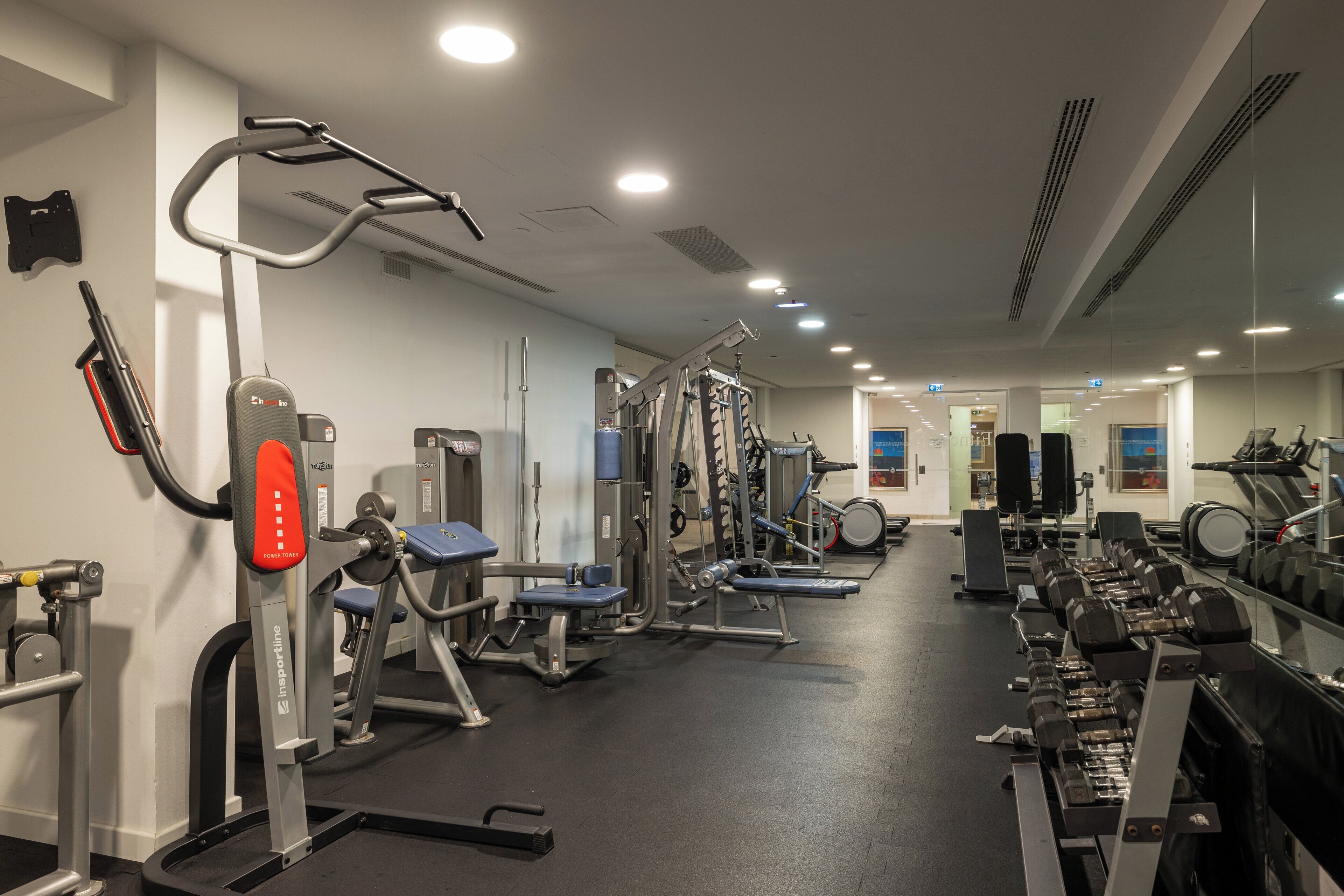 A gym with various exercise equipment, including treadmills, weight machines, and dumbbells.