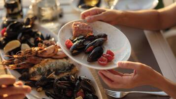A dining table with seafood dishes, including mussels and shrimp, and a wine glass.