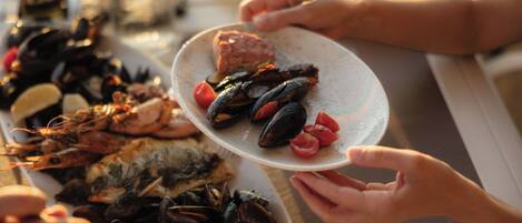 Une table à manger avec des plats de fruits de mer, notamment des moules et des crevettes, et un verre à vin.