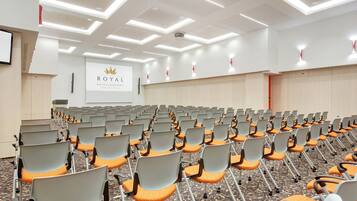 Een vergaderruimte met rijen stoelen, een projectiescherm en een bord met Royal Hotels & Resort in Dubrovnik, Kroatië.