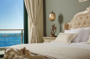 A luxurious bedroom with a large bed, ornate headboard, and a nightstand with a decorative lamp.