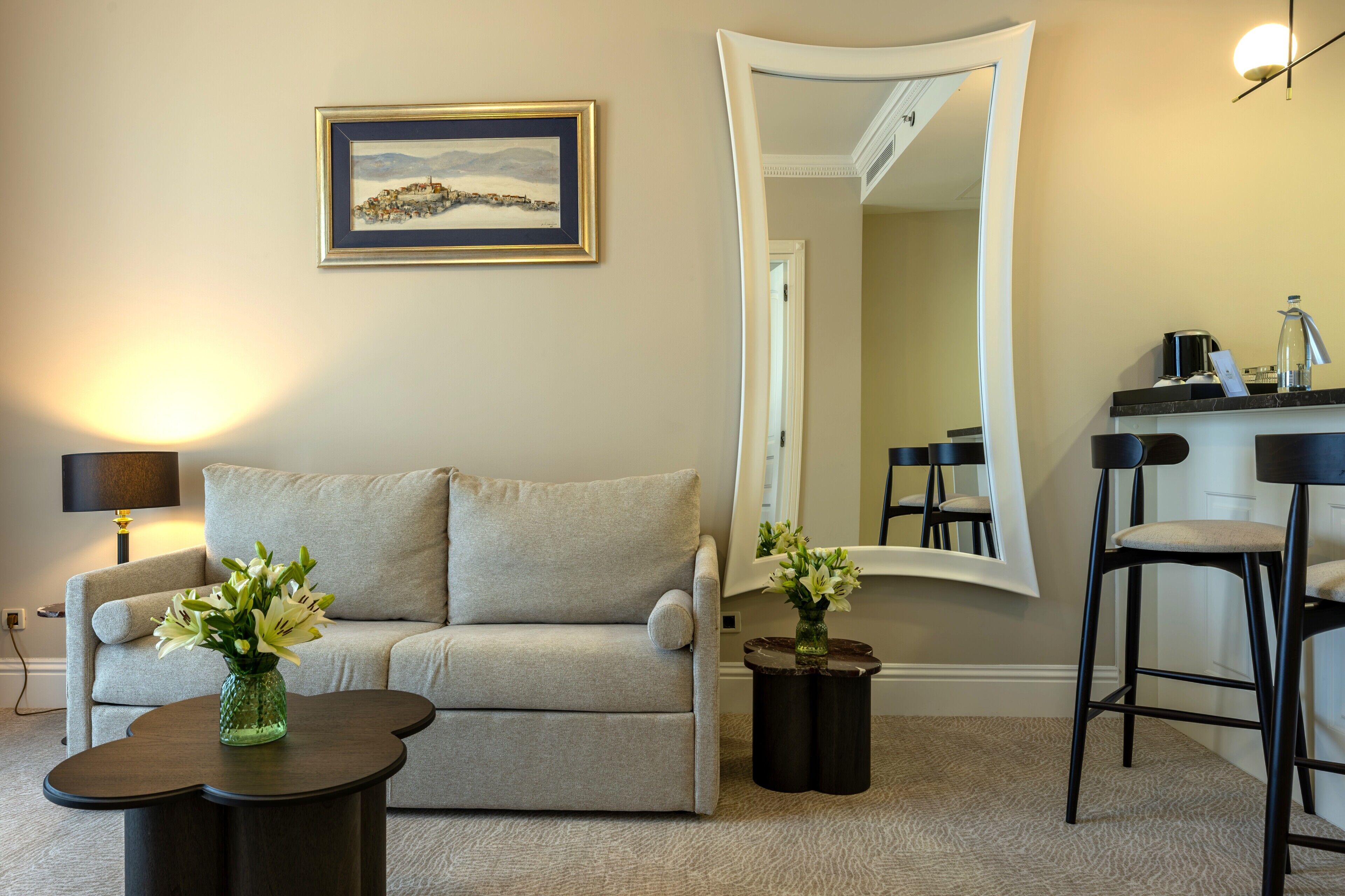 A living room with a sofa, a coffee table, a mirror, and a painting on the wall.
