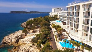 Un hotel con piscina, costa rocosa y vista al mar.