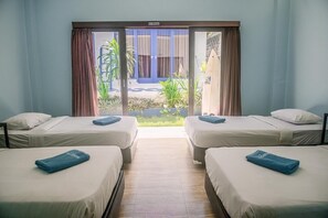 Ett hotellrum med två sängar, en skjutdörr i glas som leder ut till en trädgård och en skylt som visar att rökning inte är tillåtet.